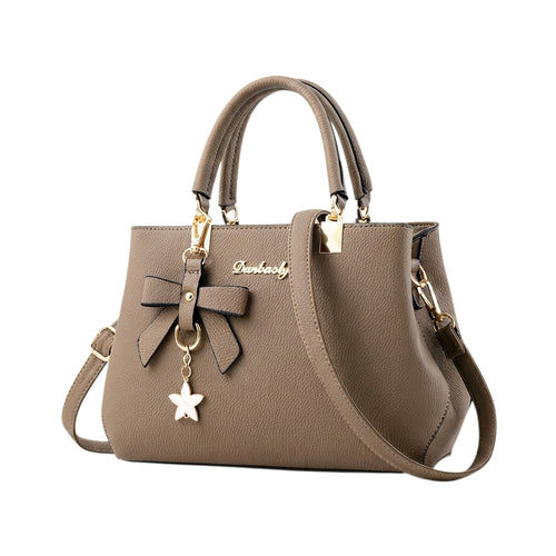 Bolso de mano Ibravacr color topo en piel sintética con lazo decorativo, dije de estrella y herrajes dorados.
