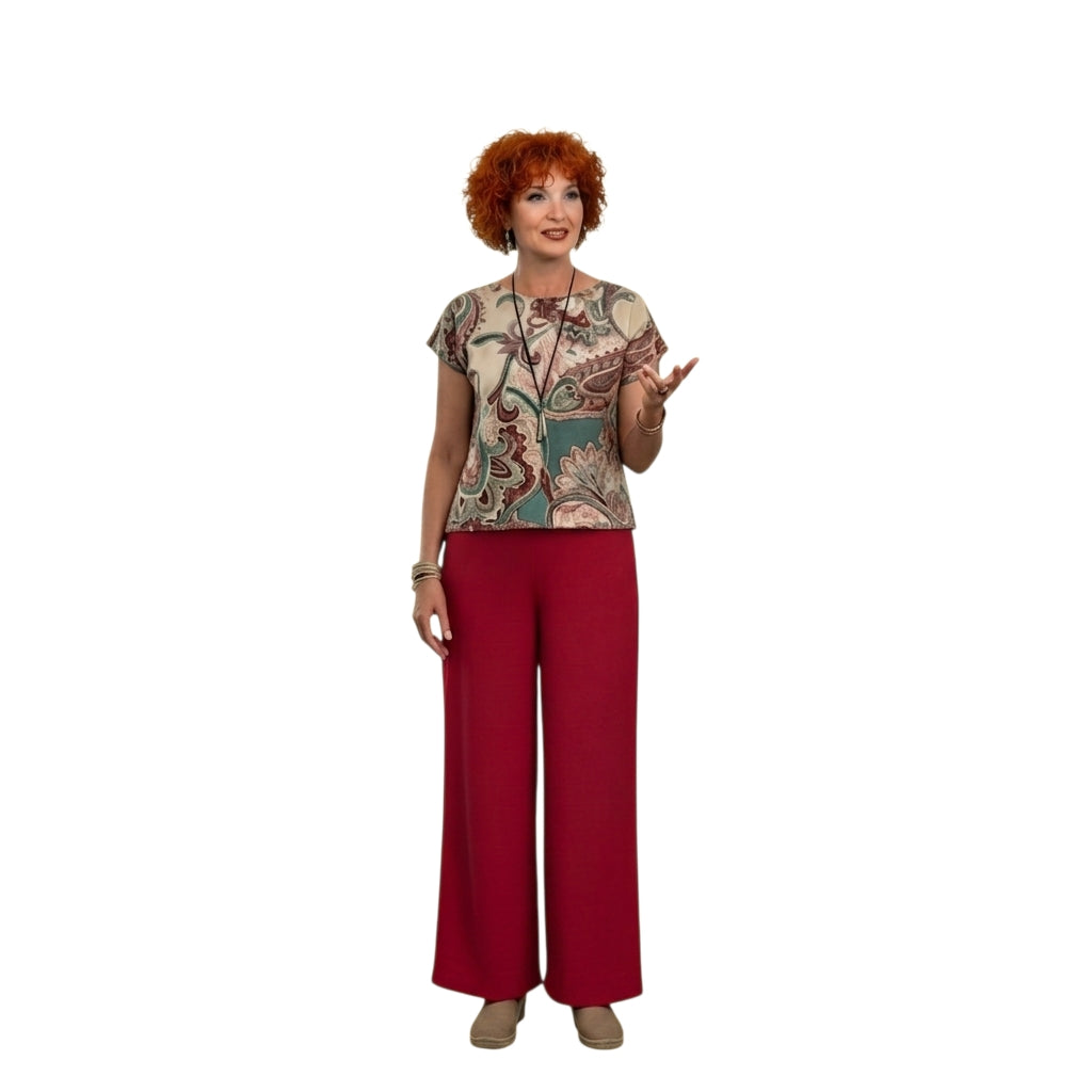 Modelo con conjunto Ibravacr de blusa estampada paisley y pantalón rojo de pierna ancha sobre fondo blanco