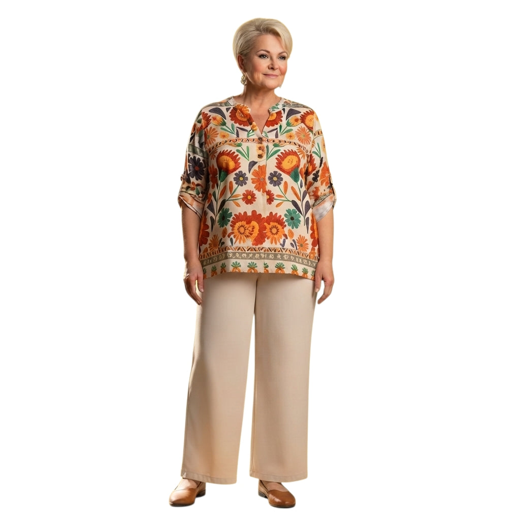 Mujer madura vistiendo conjunto Ibravacr de blusa floral naranja y pantalón beige de corte recto y fluido