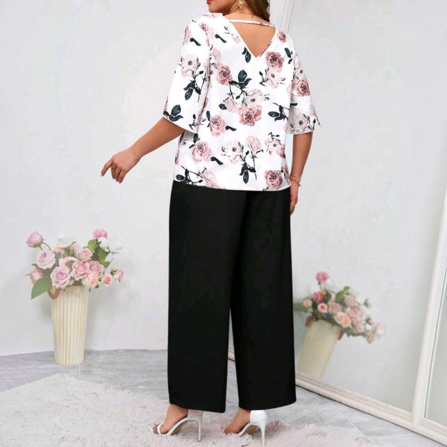 Conjunto Ibravacr de blusa blanca con estampado floral y escote en V en la espalda con pantalón negro de corte recto.