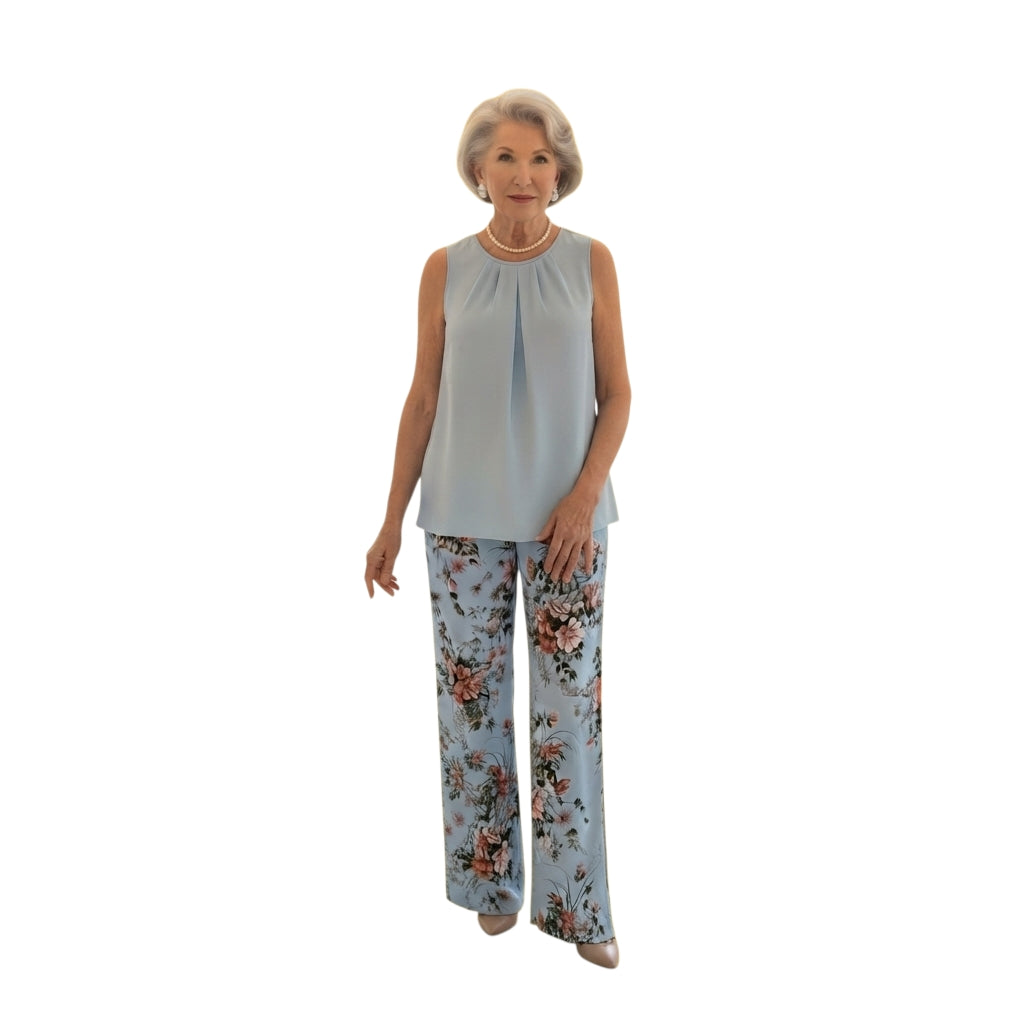 Modelo mayor luciendo conjunto Ibravacr de blusa azul cielo sin mangas y pantalón de pierna ancha con estampado floral.