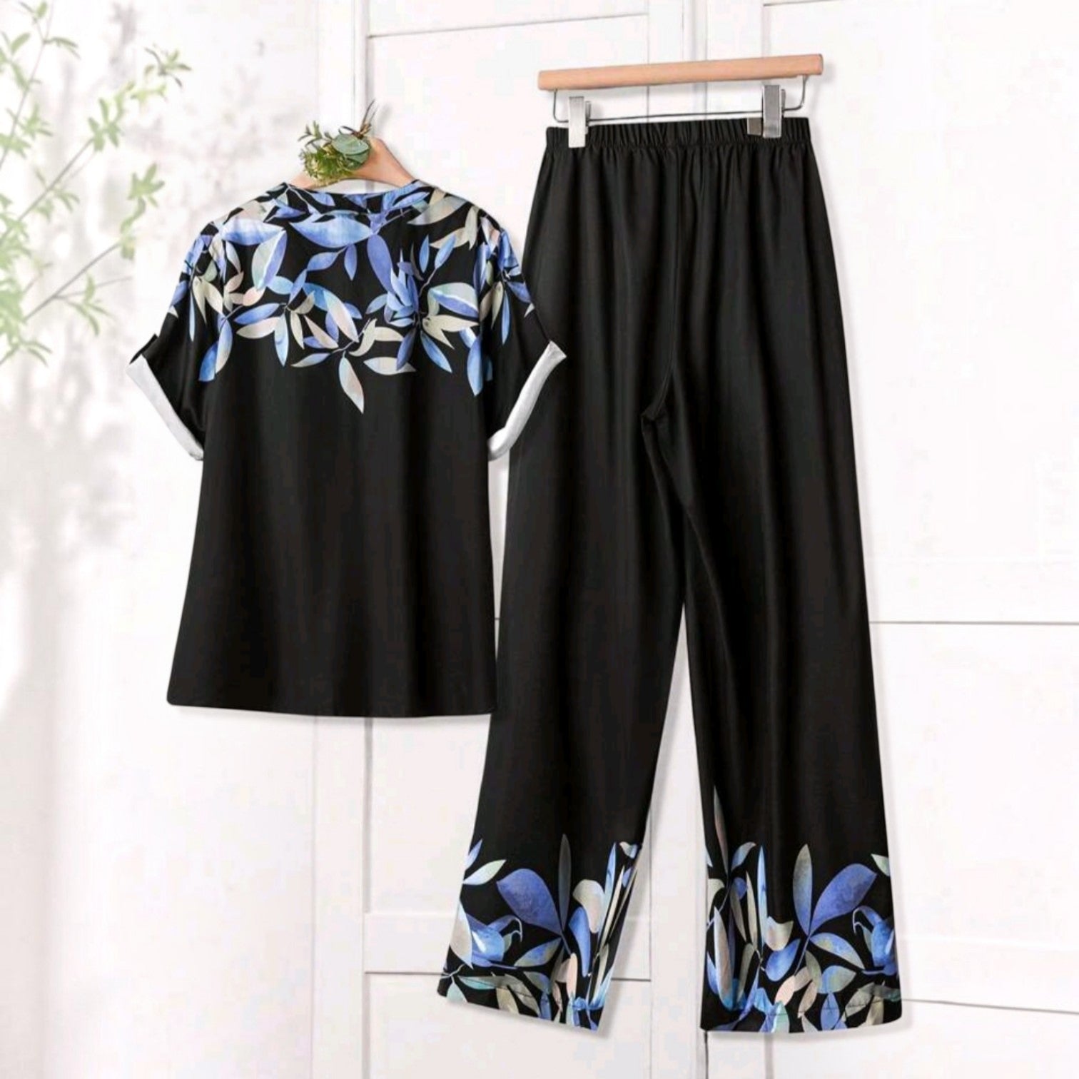 Conjunto Ibravacr de dos piezas con blusa polo y pantalón recto, estampado botánico azul sobre fondo negro ligero.