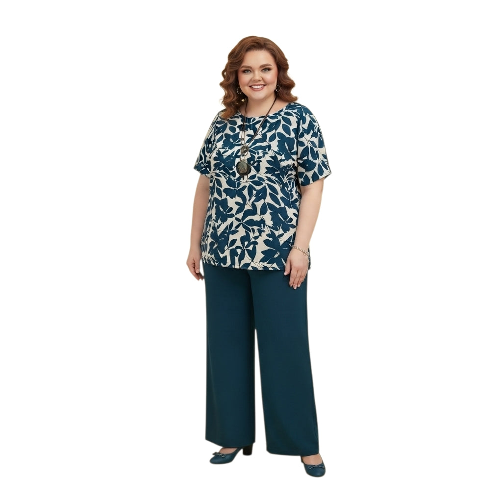 Modelo sonriente vistiendo conjunto Ibravacr de dos piezas con blusa estampada botánica azul y pantalón azul petróleo.