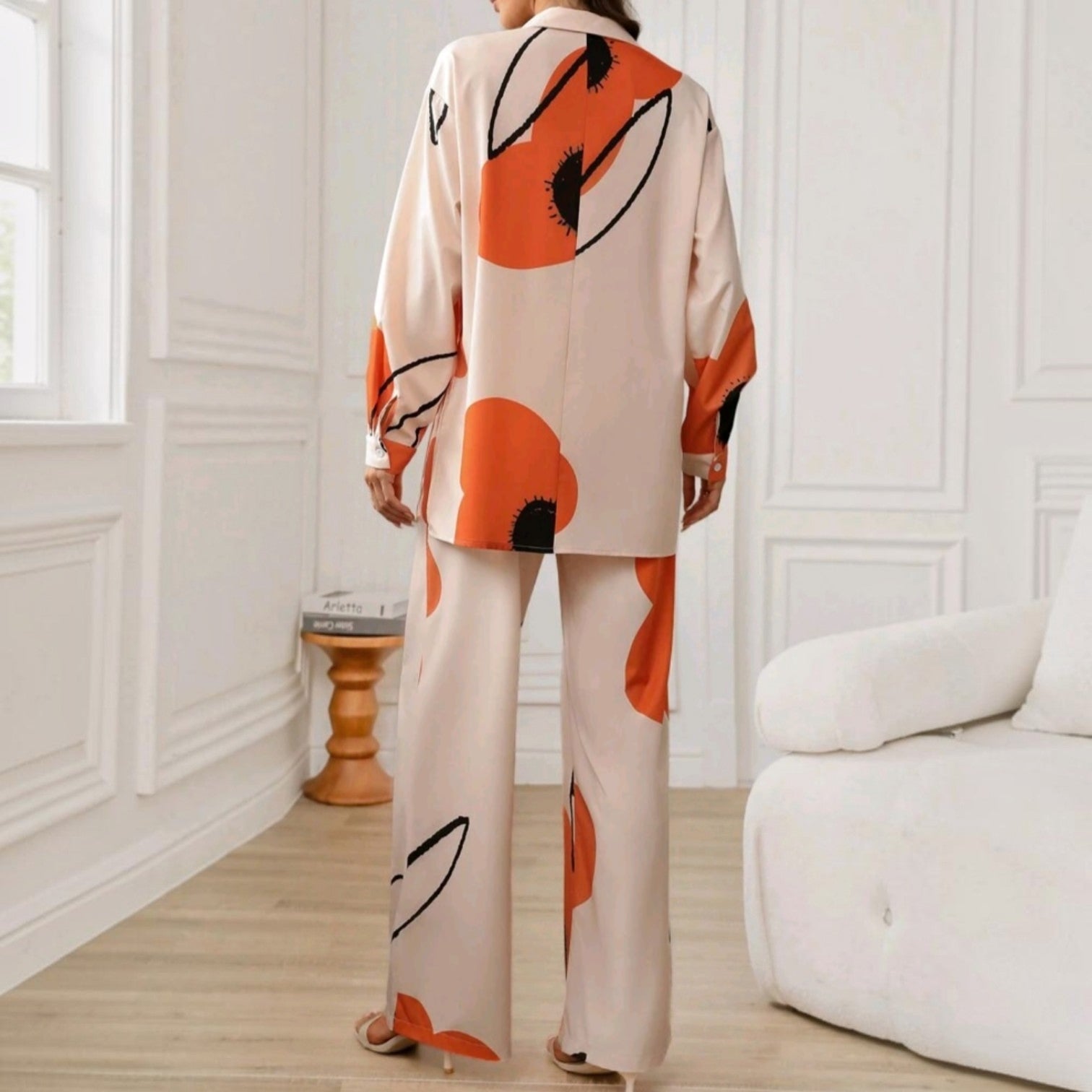 Vista trasera del conjunto Ibravacr de dos piezas con estampado floral abstracto naranja y negro sobre base crema.