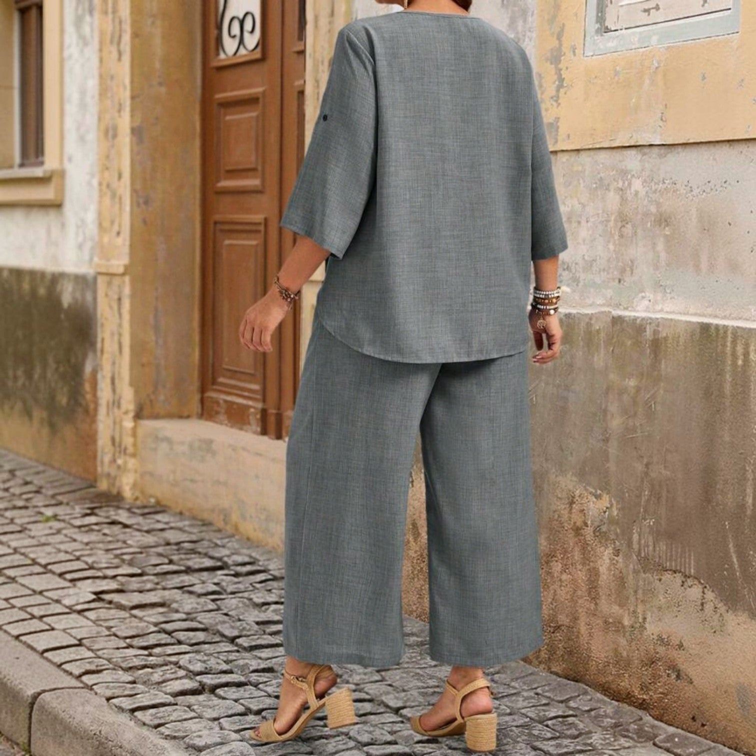 Vista trasera de mujer vistiendo conjunto Ibravacr de dos piezas gris con blusa holgada y pantalón ancho de pierna