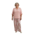 Modelo sonriente vistiendo un conjunto Ibravacr rosa de dos piezas con blusa de cuello en V y pantalón de pierna ancha