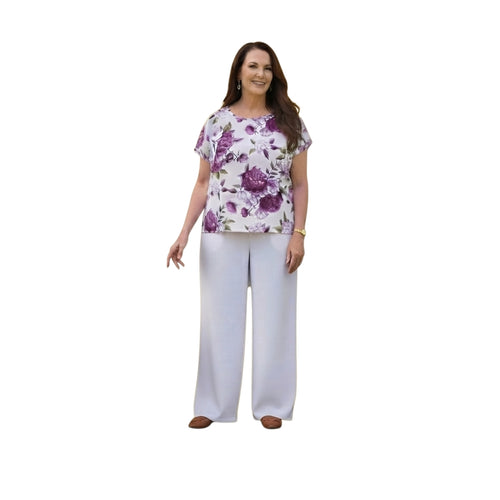 Mujer vistiendo conjunto Ibravacr de blusa floral violeta y pantalón de vestir blanco de corte recto