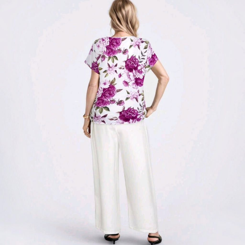 Vista trasera del conjunto Ibravacr con blusa de estampado floral violeta y pantalones blancos de corte recto.