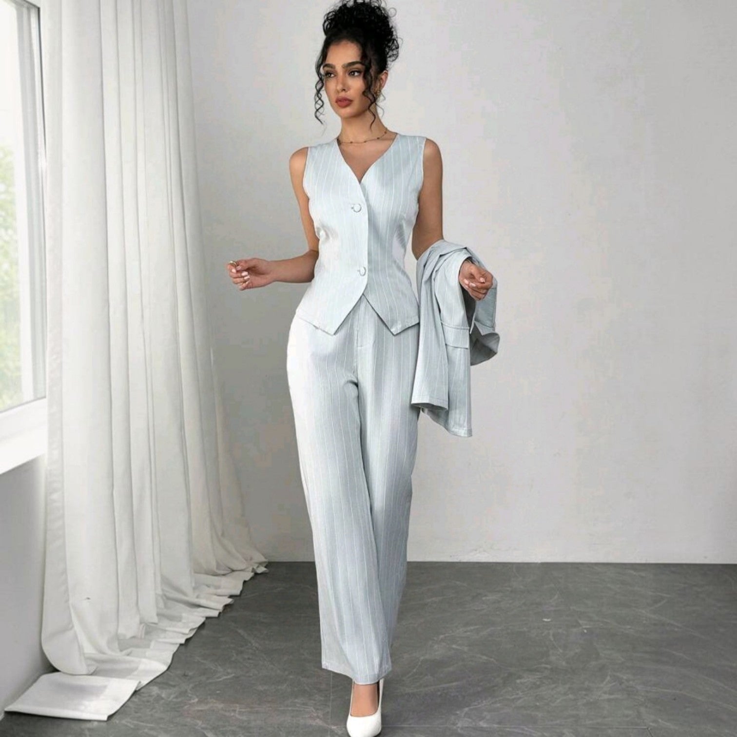 Modelo vistiendo conjunto formal Ibravacr de tres piezas azul claro con rayas verticales, chaleco y pantalón recto.