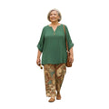 Mujer madura vistiendo conjunto Ibravacr de blusa verde bosque con botones y pantalón fluido estampado estilo paisley.