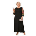 Mujer madura con vestido largo negro Ibravacr de corte fluido y mangas transparentes con bordados florales coloridos.