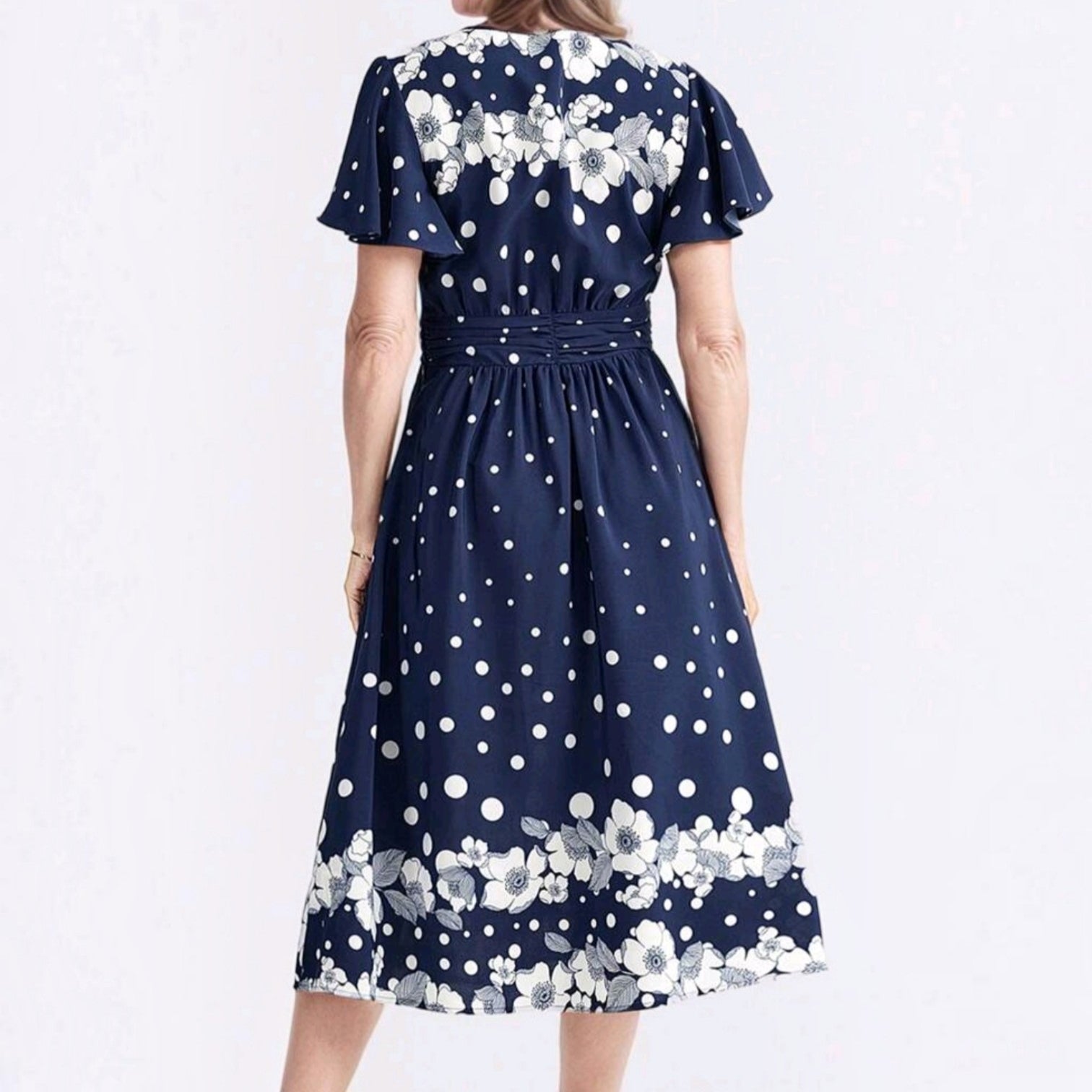 Vista trasera del vestido midi Ibravacr azul marino con estampado de lunares blancos y flores en el dobladillo