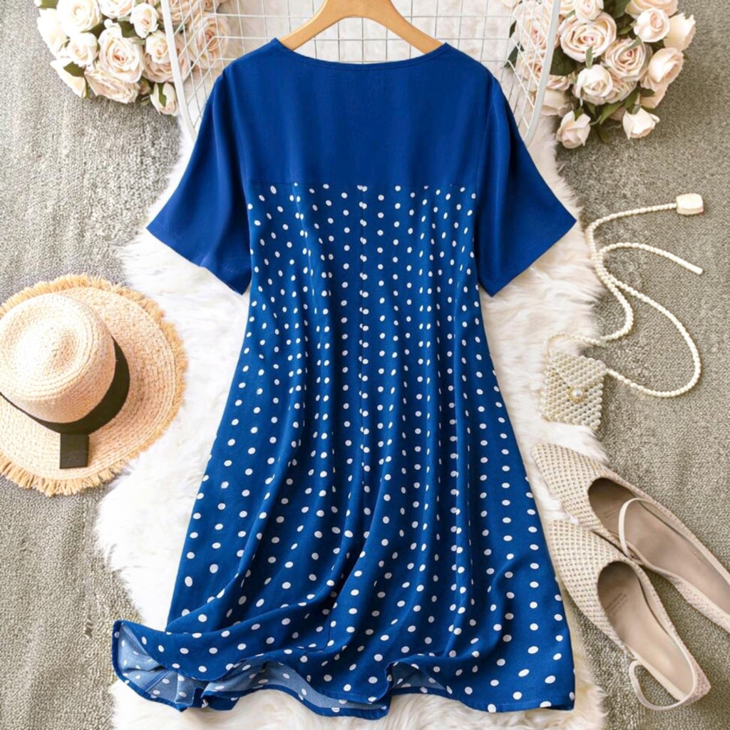 Vestido midi Ibravacr azul con lunares blancos, manga corta y cuello redondo sobre una alfombra de piel sintética.