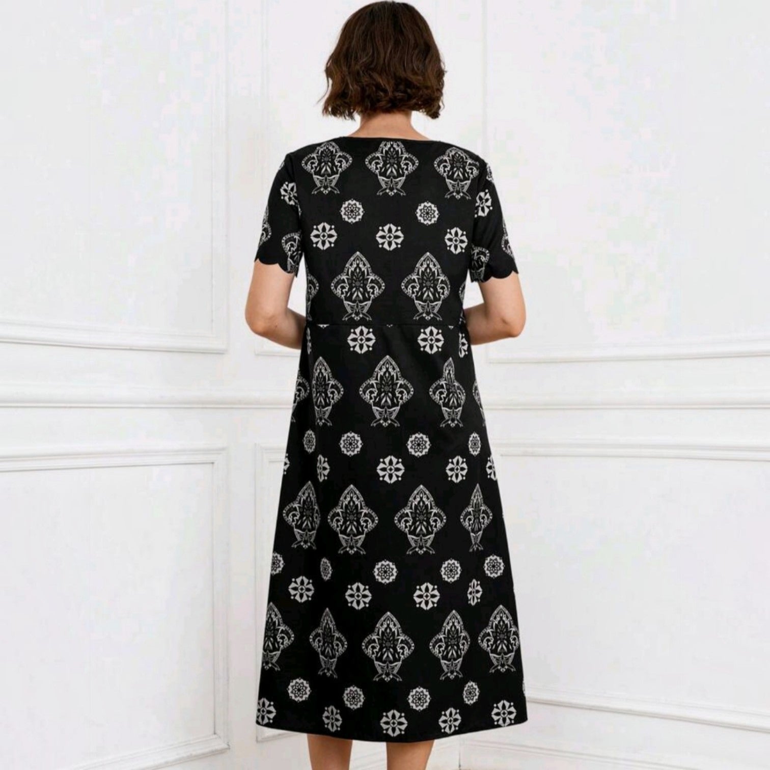 Vestido midi Ibravacr negro con estampado geométrico y floral blanco, manga corta y corte fluido visto desde atrás