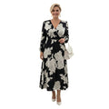 Modelo sonriente usando vestido midi Ibravacr con estampado floral blanco y negro, escote cruzado y mangas largas.