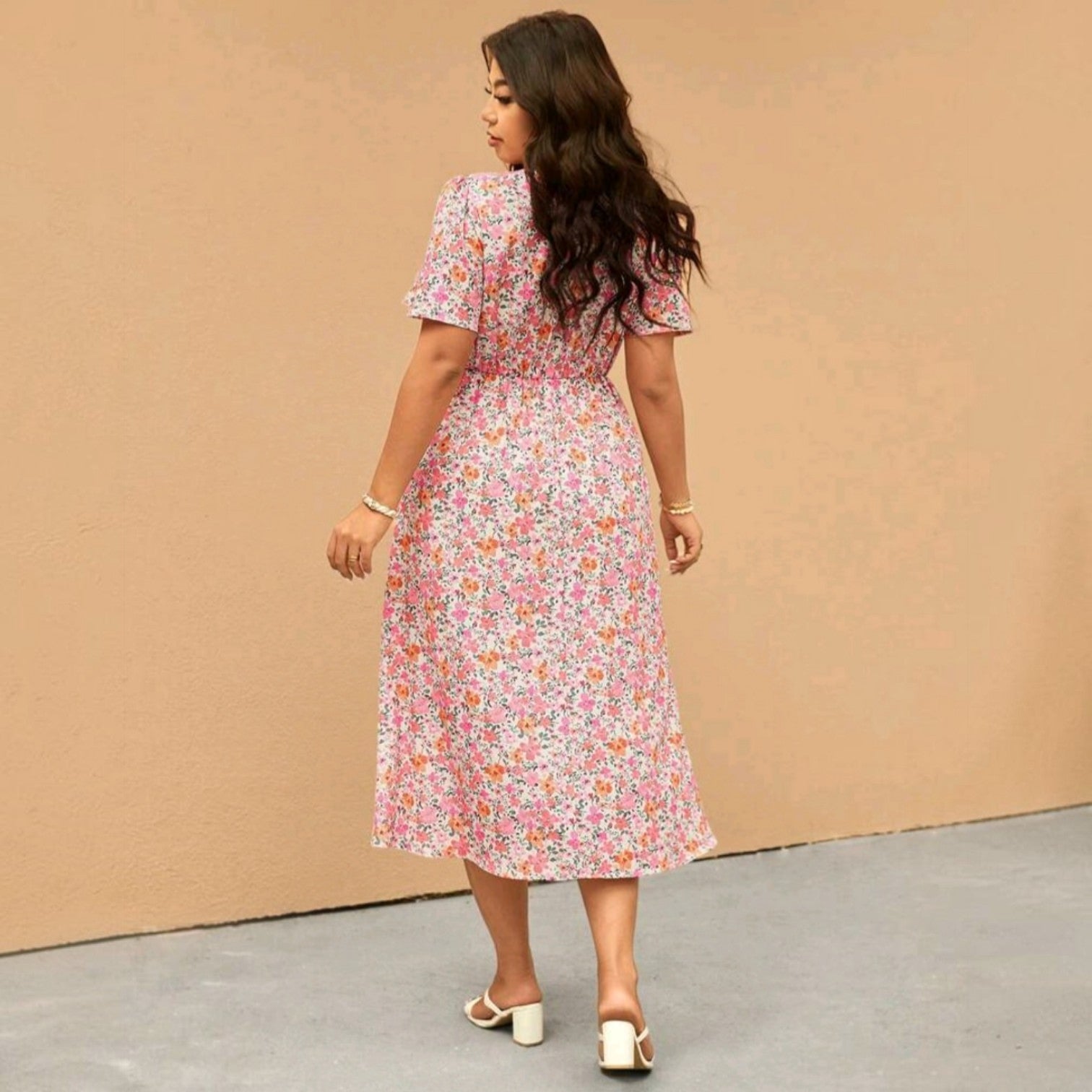 Vista trasera de una modelo usando un vestido midi floral Ibravacr con falda fluida y mangas cortas en tonos suaves.