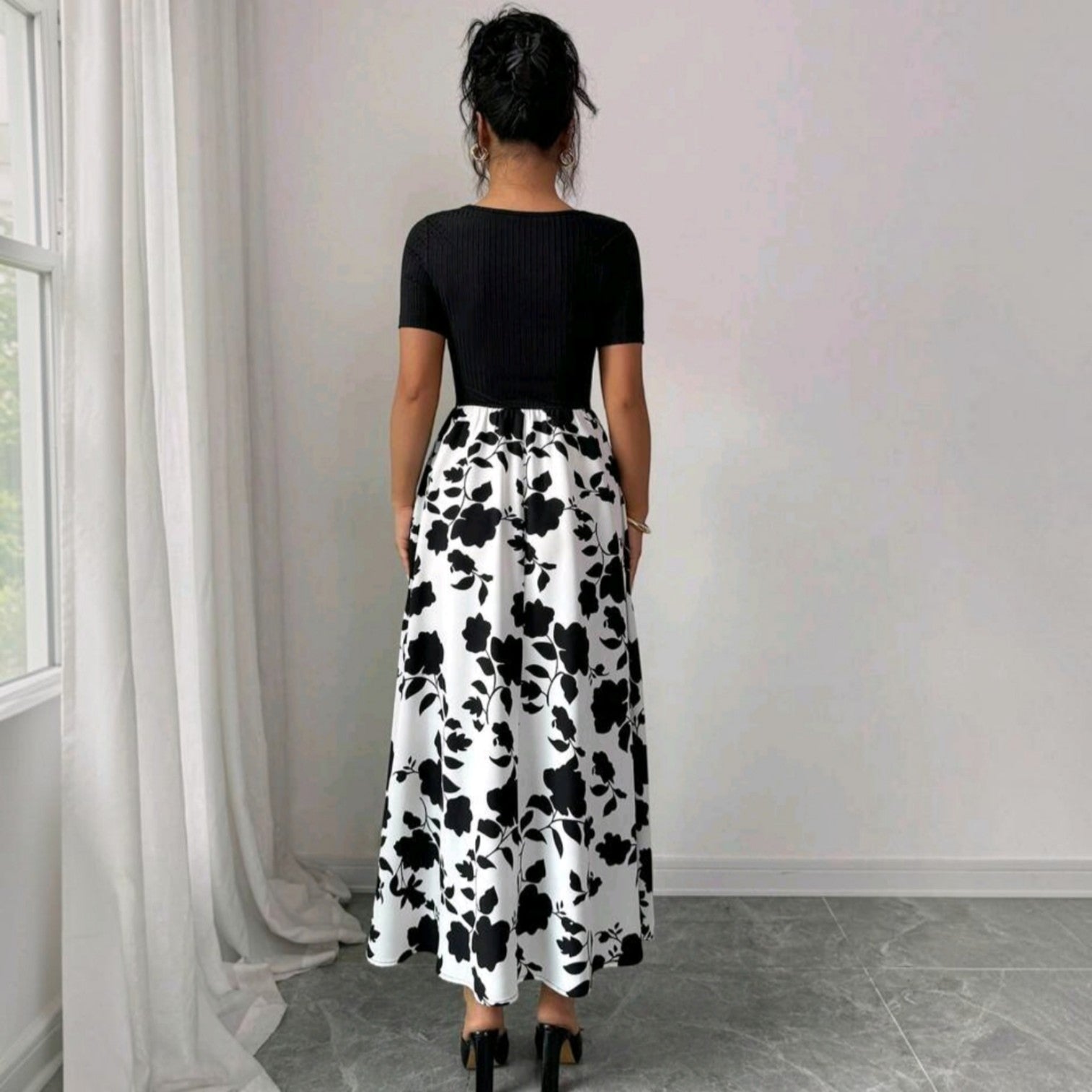 Vista trasera de un vestido midi Ibravacr de dos piezas con top negro acanalado y falda acampanada con estampado floral