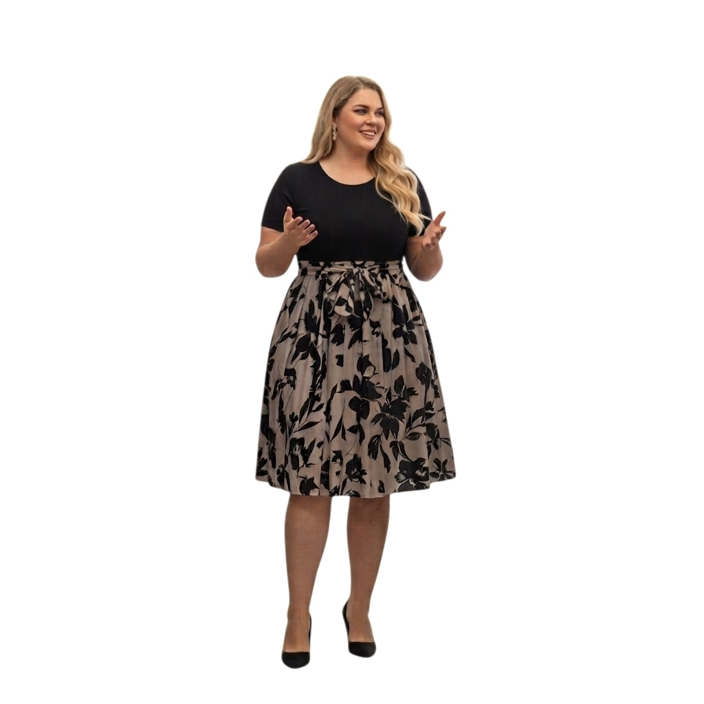 Modelo sonriente vistiendo un vestido midi Ibravacr con cuerpo negro de manga corta y falda floral con lazo en cintura