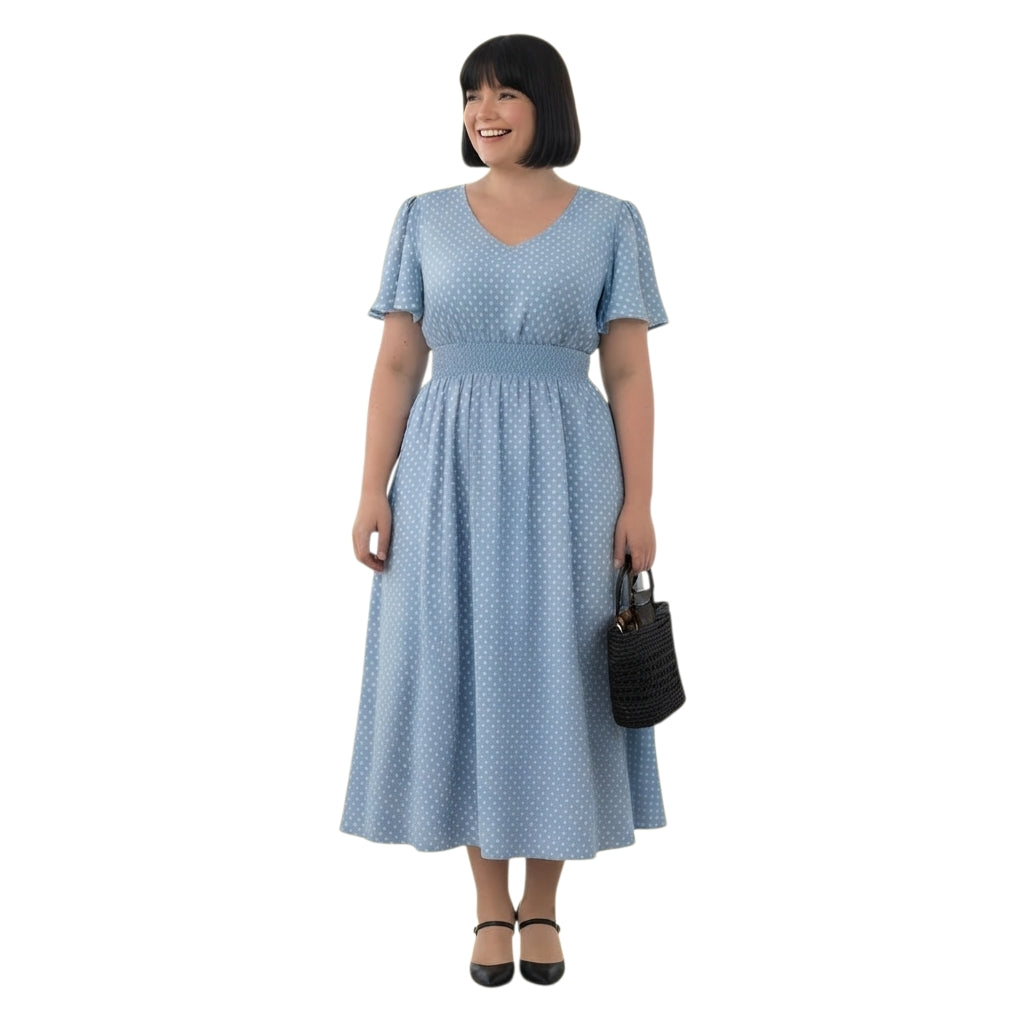 Modelo sonriente vistiendo vestido midi Ibravacr azul celeste con lunares blancos, escote en V y cintura elástica.
