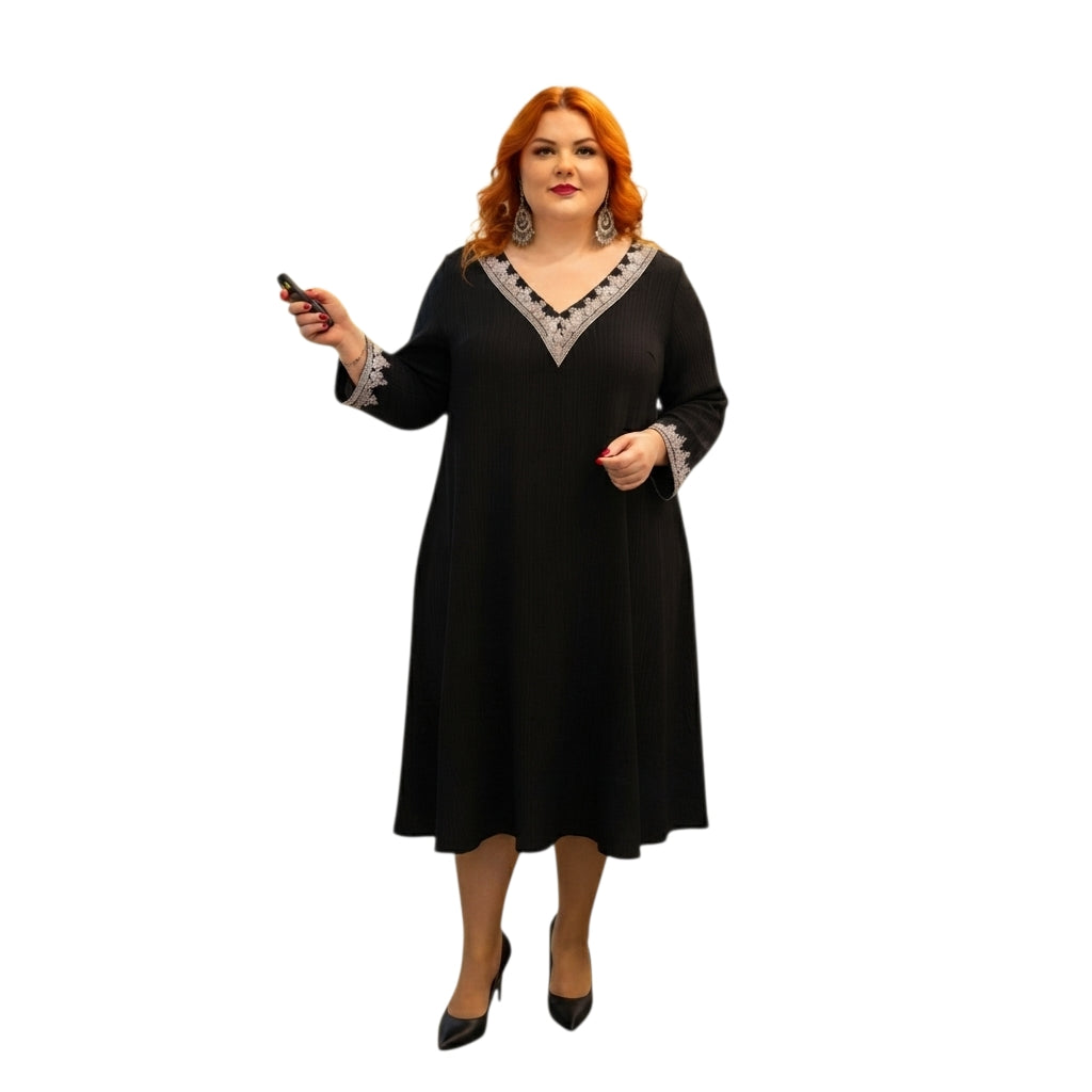 Modelo de talla grande vistiendo un vestido midi negro Ibravacr con bordados en escote y puños, corte holgado.