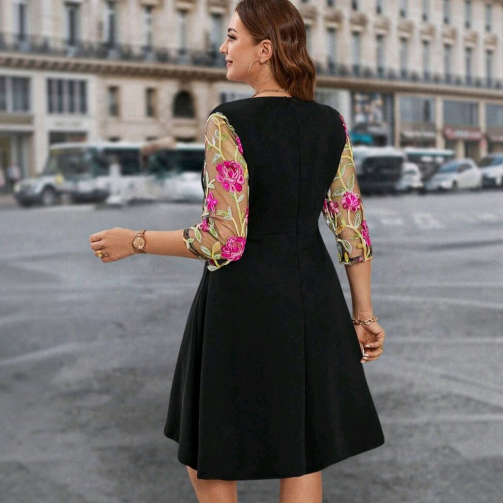 Vestido midi negro Ibravacr con mangas de malla transparente y bordado floral rosa y verde en un entorno urbano