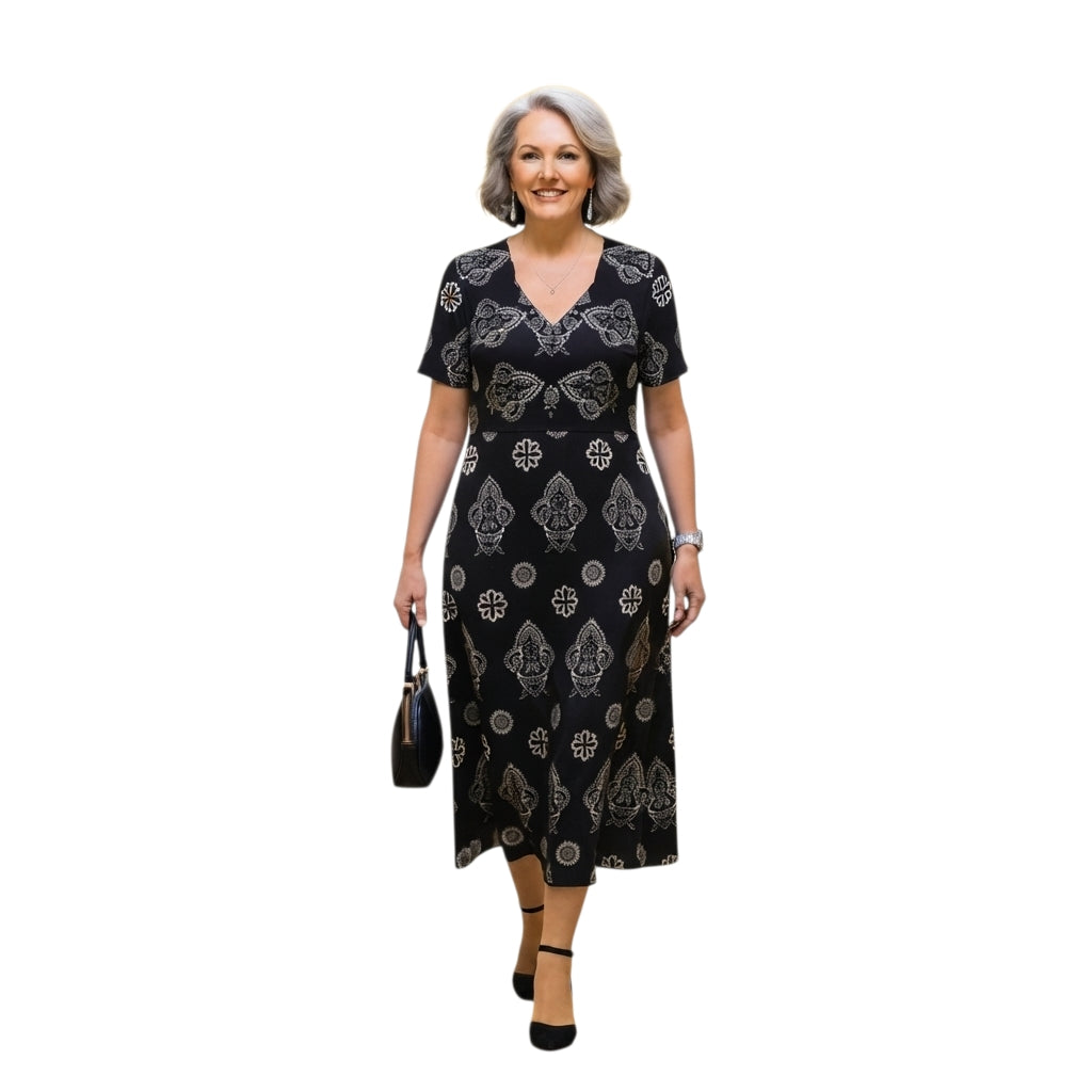 Mujer madura vistiendo un vestido midi negro Ibravacr con estampado geométrico y floral, escote en V y mangas cortas.