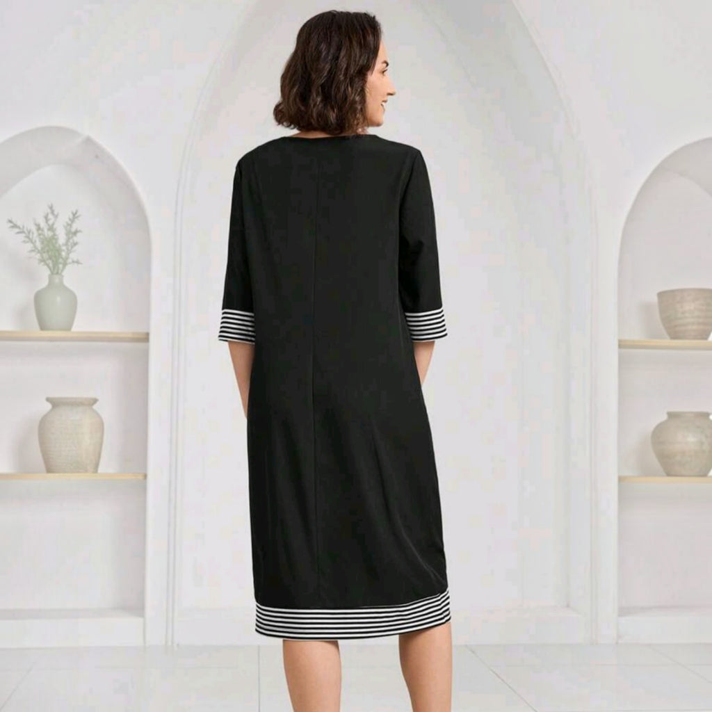 Vista trasera del vestido midi negro Ibravacr con mangas tres cuartos y detalles de rayas blancas en el bajo