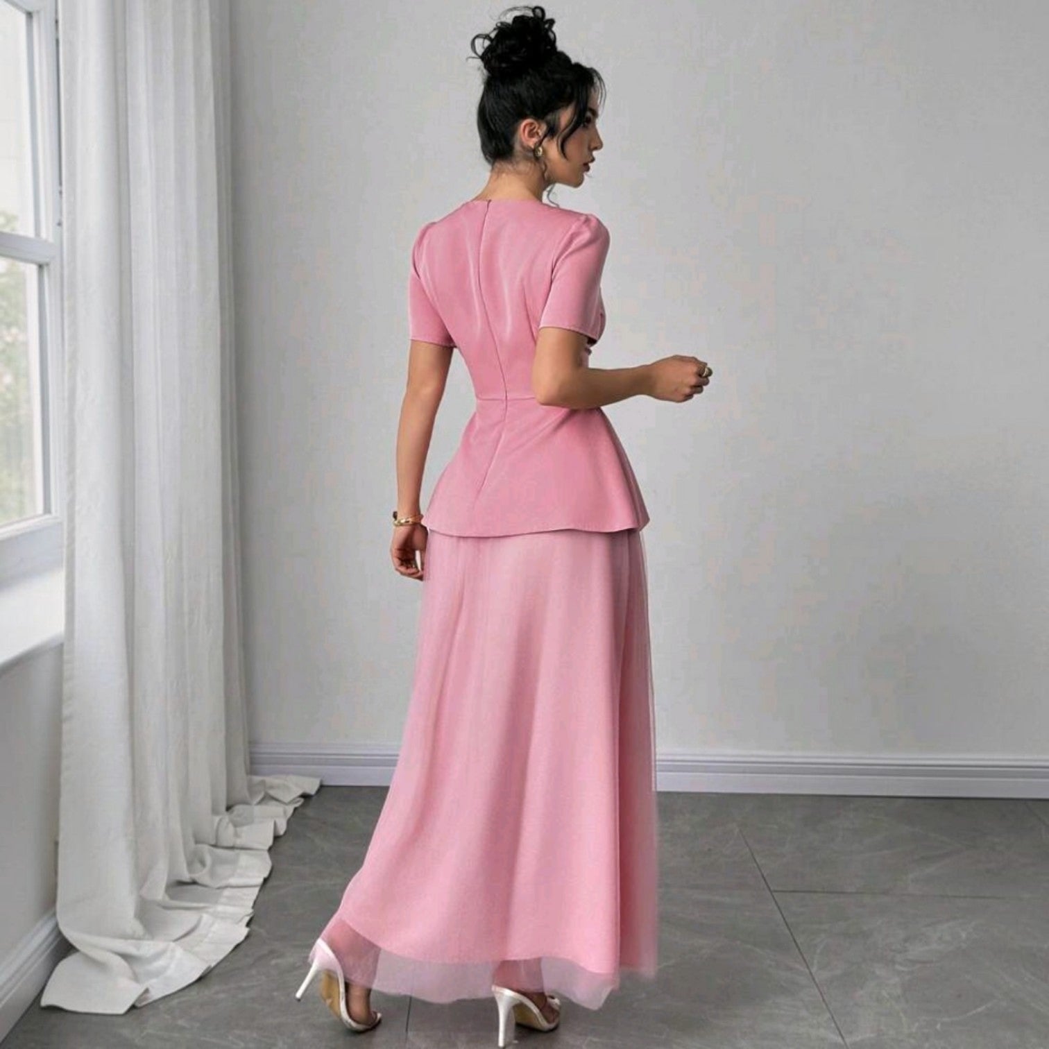 Vista trasera de un vestido midi Ibravacr rosa empolvado con detalle peplum, falda de tul y mangas cortas.